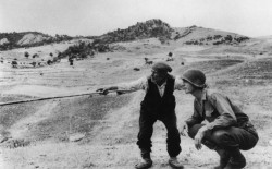 Seconda guerra mondiale, Troina, Sicilia. Un anziano indica a un ufficiale americano quale strada hanno percorso i tedeschi. Agosto 1943. © Robert Capa / International Center of Photography / Magnum Photos